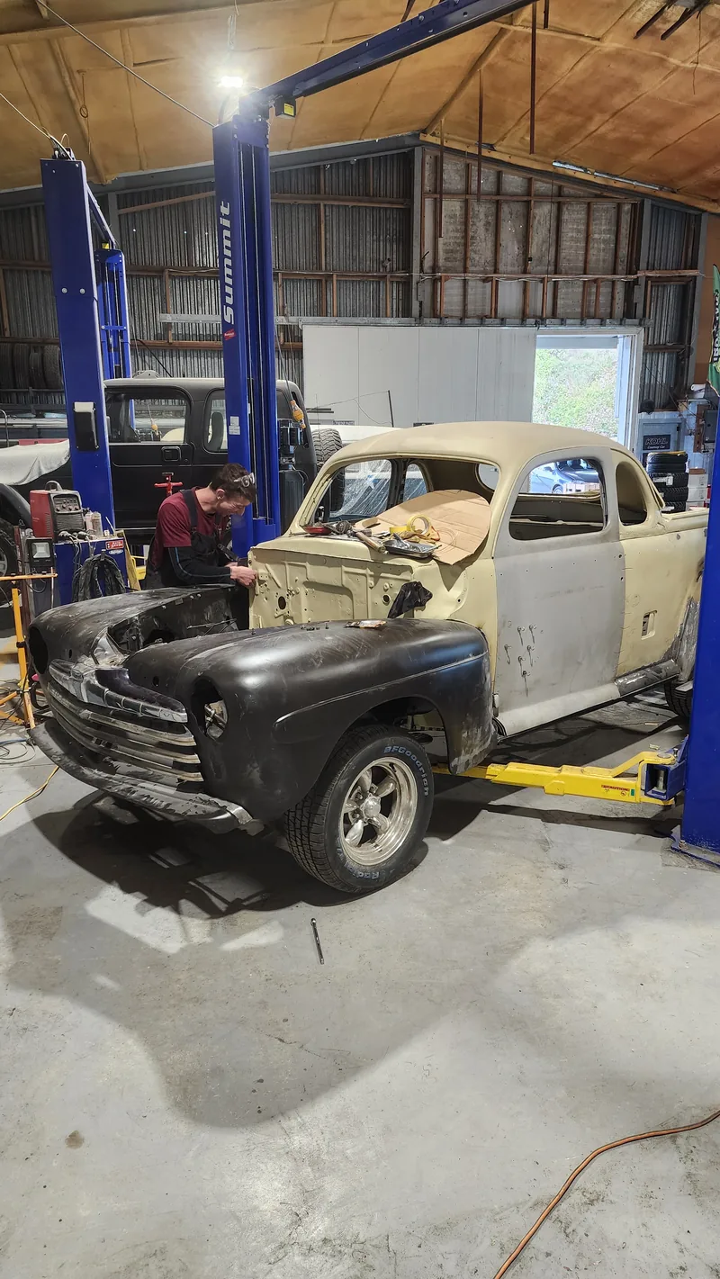 The 1946 Ford ute on the hoist with the front guards and grille refitted, cab still in primer