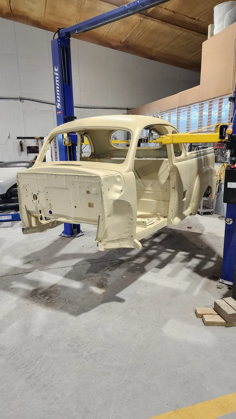 The 1946 Ford ute cab shell stripped to bare metal and sealed in epoxy primer, up on the two-post hoist