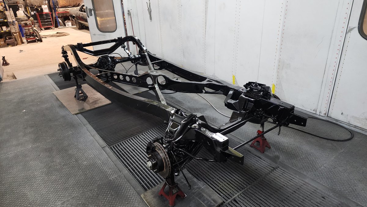 The fabricated 1946 Ford ute chassis in gloss black on stands at Kohl Customs, showing the independent front suspension and disc brakes