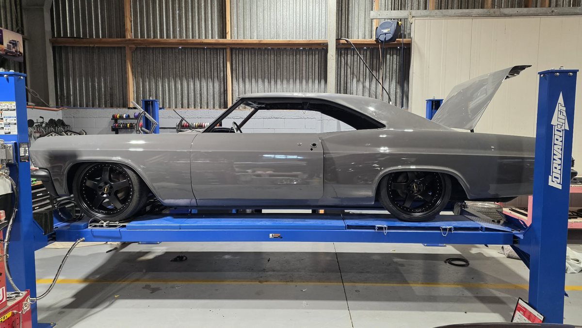 Sachin's 1965 Chevrolet Impala finished in solid grey, side profile, sitting low on air suspension at the Kohl Customs workshop