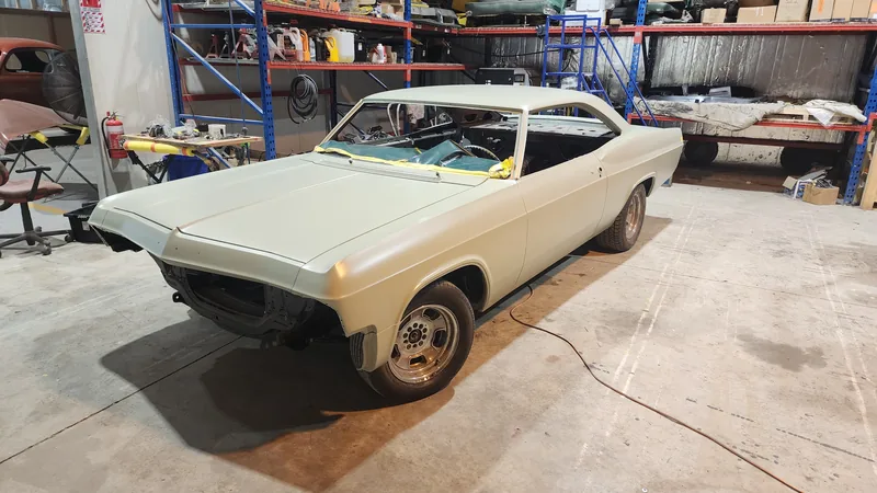 The 1965 Impala in primer, front three-quarter view inside the Kohl Customs workshop