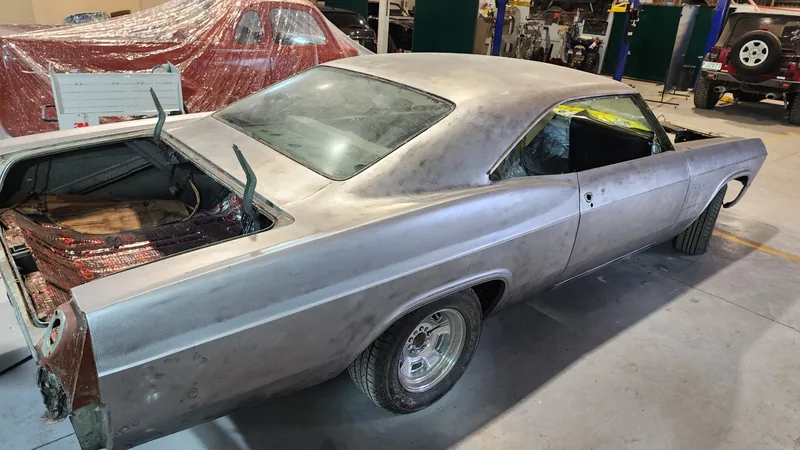 The Impala stripped back to bare metal in the Kohl Customs workshop, rear quarter and roof line showing