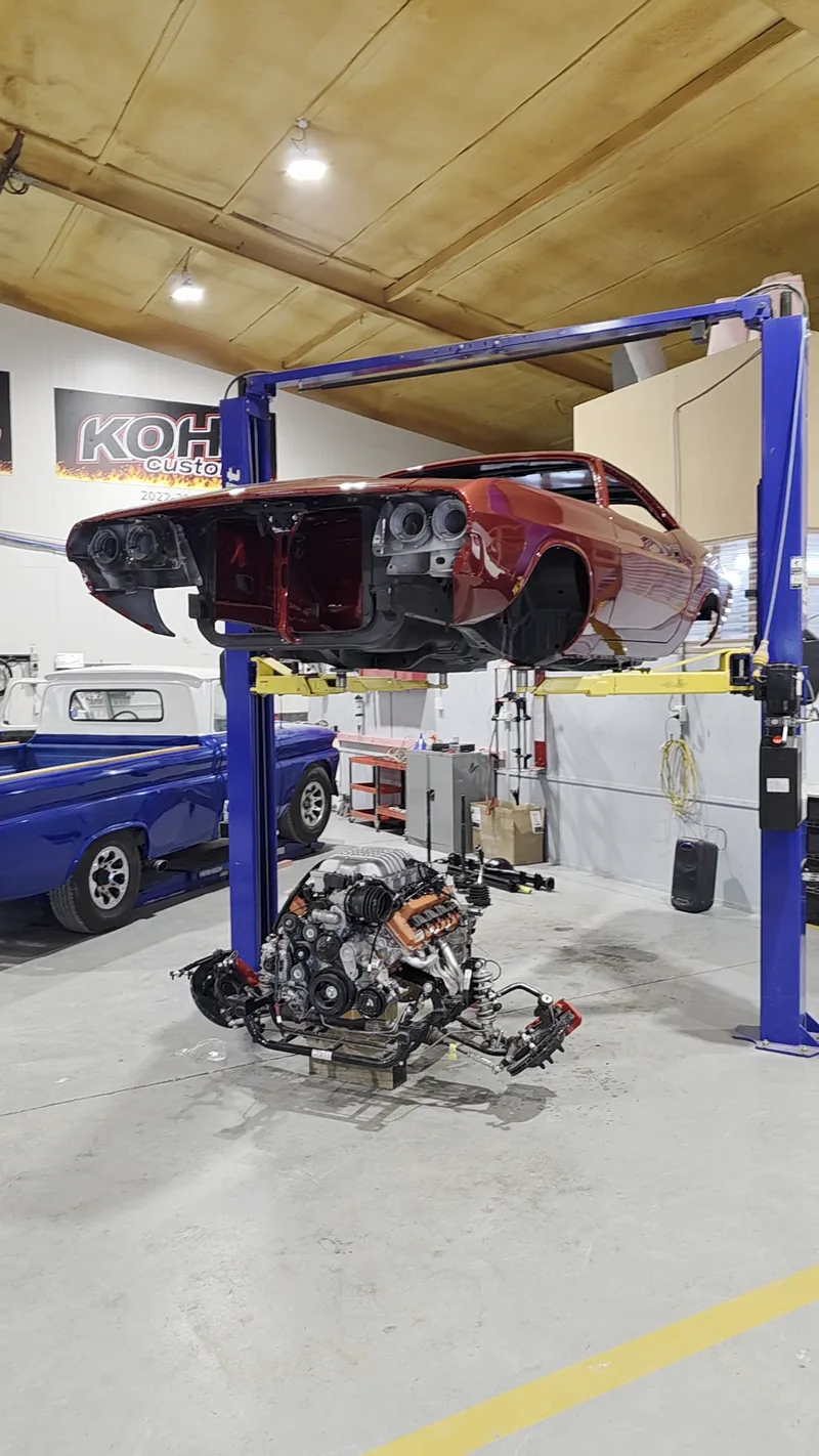 The 1971 Dodge Challenger body up on the hoist at Kohl Customs with the Hellcat driveline on the floor beneath it