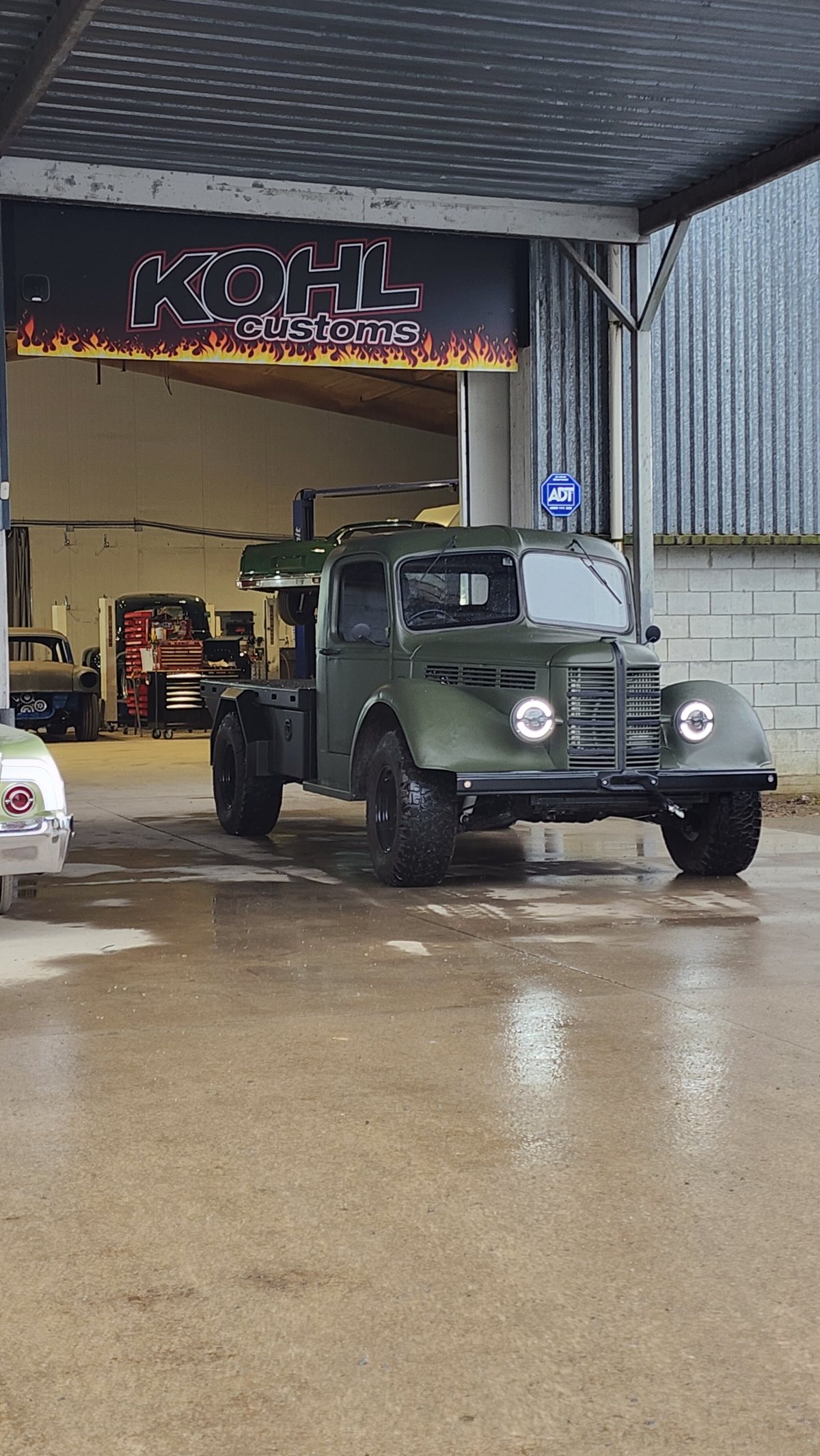 The finished army green Bedford K cab under the Kohl Customs signage at Kuku