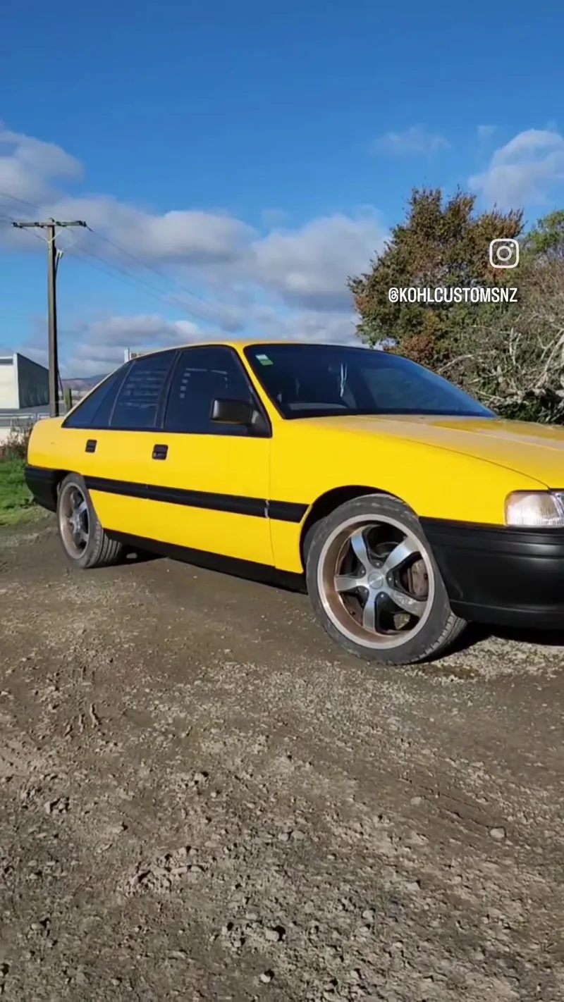 Rear three-quarter view of the finished VN Commodore in Devil Yellow on gravel outside Kohl Customs
