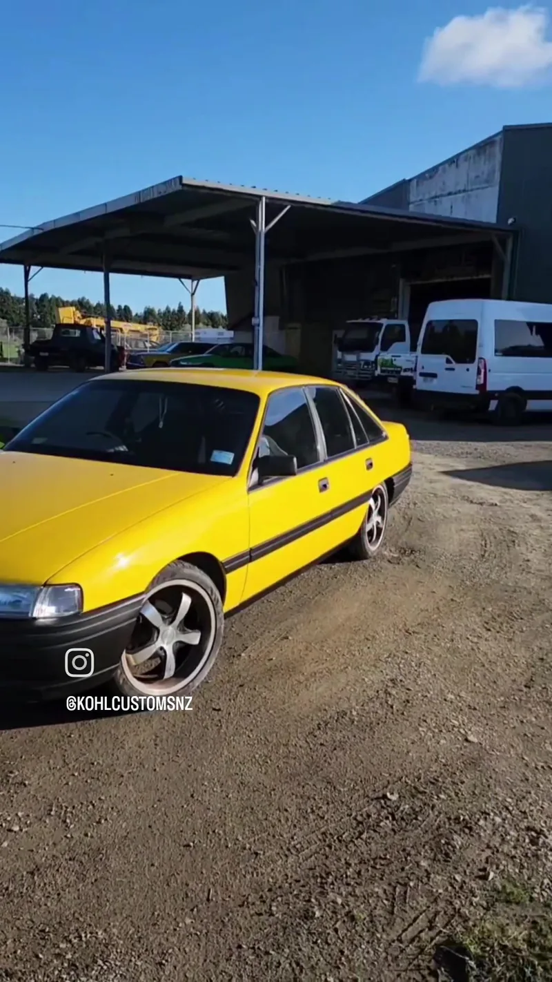 Side profile of the finished yellow VN Commodore showing the blacked-out lower body and bronze wheels