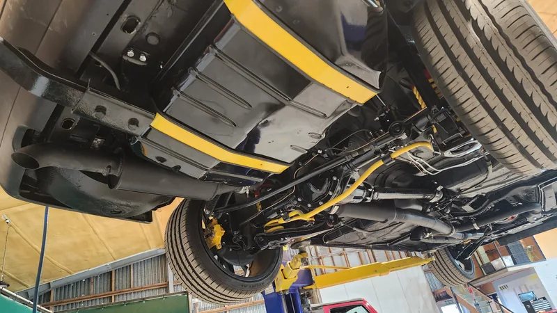 The finished underside of the VN Commodore showing stainless exhaust, yellow sway bar and painted subframes