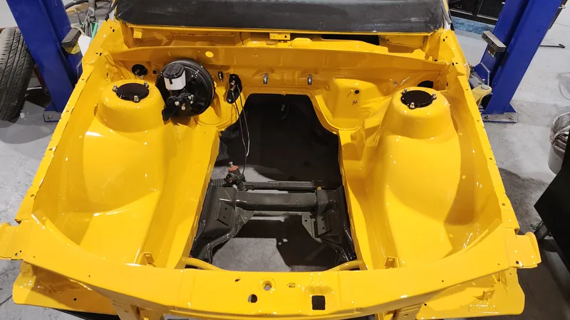 The freshly painted yellow engine bay of the VN Commodore, still empty