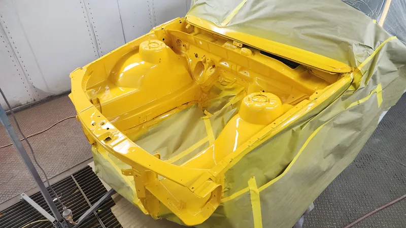 The VN Commodore shell freshly painted in HSV Devil Yellow, masked, with the interior still out