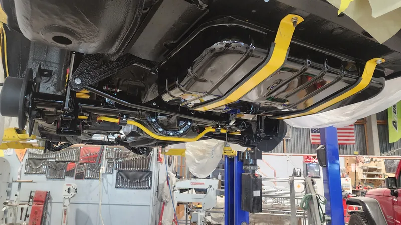 The underside of the VN Commodore painted in Devil Yellow up on the two-post hoist