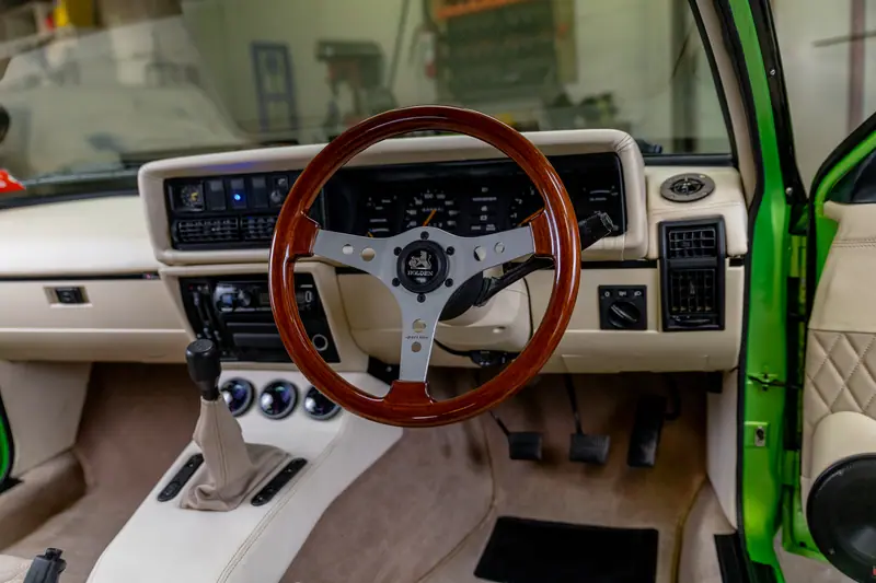 Dashboard of the VH Commodore with a wood-rim steering wheel on a polished three-spoke centre and cream trim