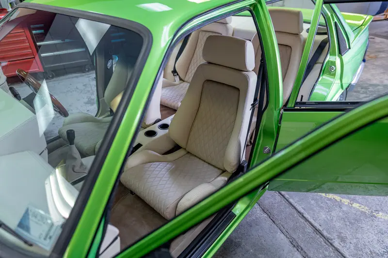 Driver's door open on the green VH Commodore showing the cream diamond-stitch interior against the candy green paint