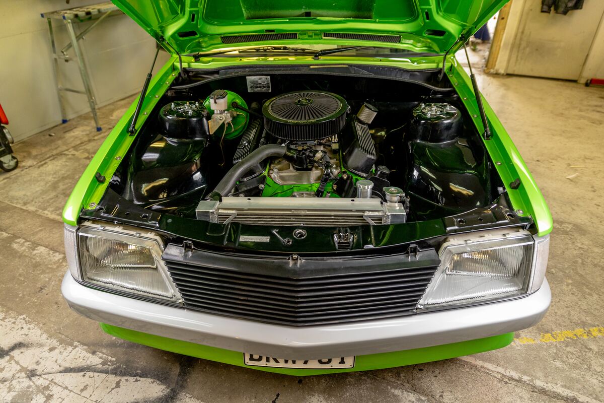 Engine bay of the restored VH Commodore with the bonnet up, painted bay, polished air cleaner and tidy plumbing