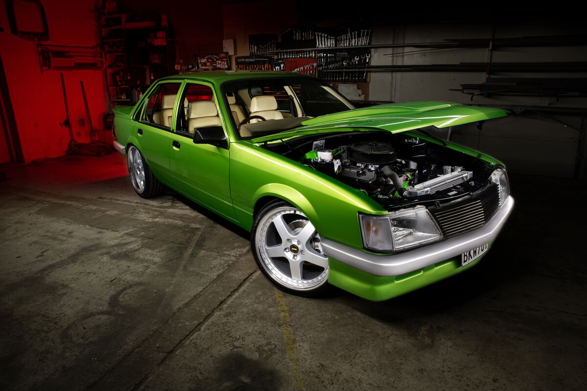 Restored 1983 VH Holden Commodore in candy green, bonnet up, under red workshop lighting at the Kohl Customs workshop in Kuku, Levin