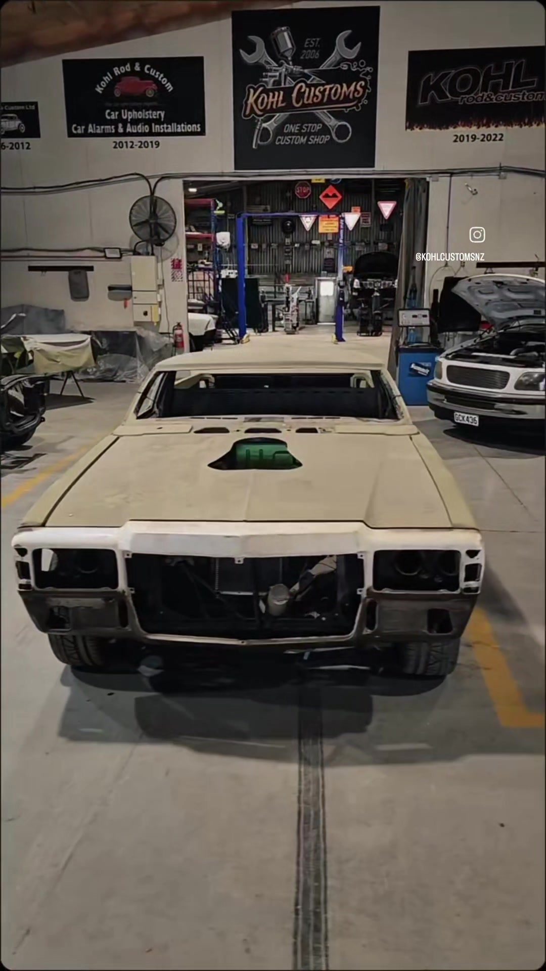 The chopped HJ Holden ute in primer, front on and sitting low on the workshop floor at Kohl Customs